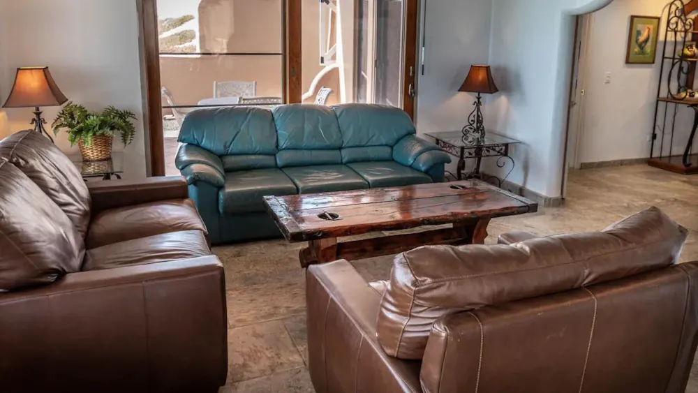 Vintage-style living room featuring three leather sofas arranged around a central wooden table